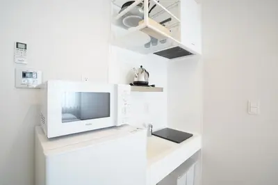 a white kitchen with a tv on a counter at U-Hotel Takadanobaba in Tokyo