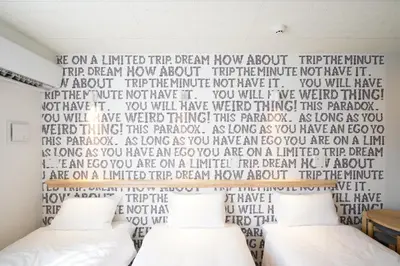 a bedroom with a bed with a wall with a heart mural at U-Hotel Takadanobaba in Tokyo