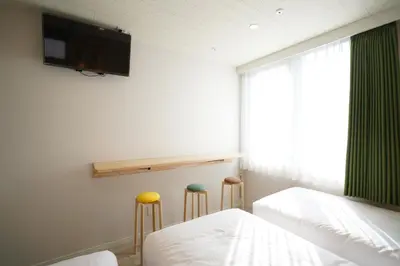 a bedroom with two stools and a tv on the wall at U-Hotel Takadanobaba in Tokyo