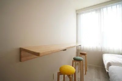 a bedroom with a shelf and two stools at U-Hotel Takadanobaba in Tokyo