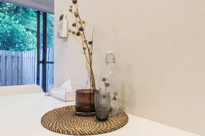 a table with a vase and a bottle on it at Dwell Urban 2B in Tokyo