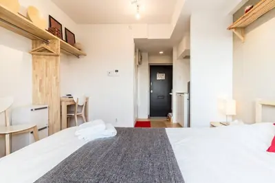 a bedroom with a large white bed and a kitchen at Dwell Urban 7C in Tokyo