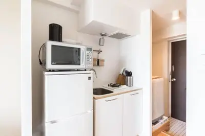 a kitchen with a microwave on top of a refrigerator at Dwell Urban 7D in Tokyo