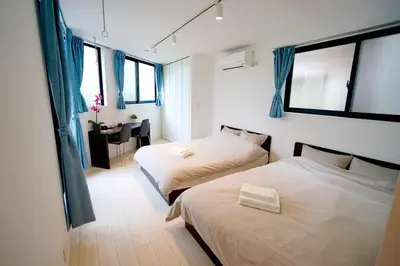a bedroom with two beds and a desk with a chair at Court Residence Tokyo Nakano in Tokyo
