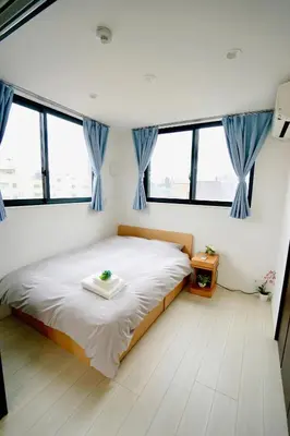 a bedroom with a large bed with blue curtains at Court Residence Tokyo Nakano in Tokyo