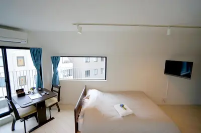 a bedroom with a bed and a desk and a window at Court Residence Tokyo Nakano in Tokyo