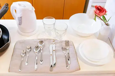 a table with silver utensils and plates and a rose at HARMONIA\u6771\u4eac\u5800\u5207 10\u540d\u5b9a\u54e190\u5e73\u7c73\u306e\u5e83\u3044Condominium in Tokyo