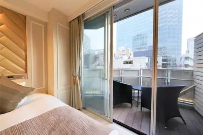 a bedroom with a bed and a balcony with a view at Centurion Hotel Residential Akasaka Station in Tokyo