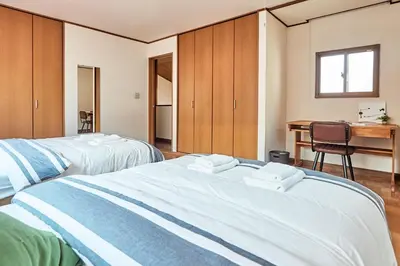 two beds in a room with a desk and a table at Villa Shibuya in Tokyo