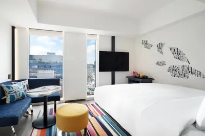 a white bedroom with a large bed and a tv at Aloft Tokyo Ginza in Tokyo