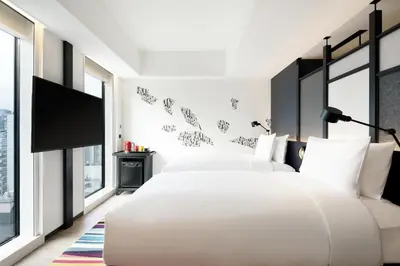 a bedroom with two beds and a flat screen tv at Aloft Tokyo Ginza in Tokyo