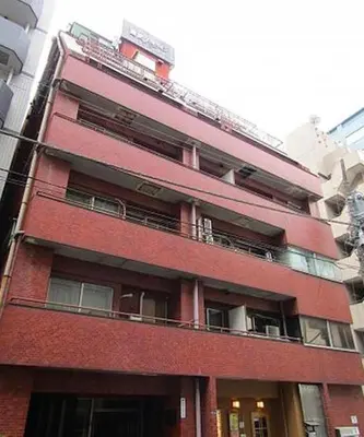a tall red brick building with a balcony at HAMAMATSUCHO Mansion #2DK# Minato-ku in Tokyo