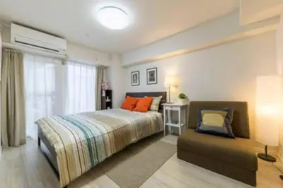 a bedroom with a bed with orange pillows and a couch at HAMAMATSUCHO Mansion #2DK# Minato-ku in Tokyo