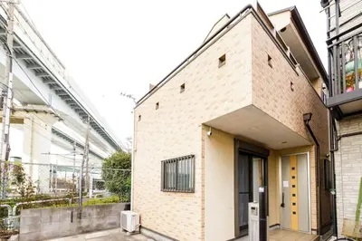 a brick building with a yellow door on a street at QIQA Residence in Tokyo