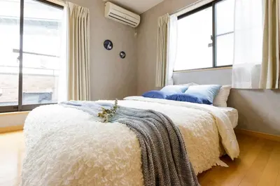 a bedroom with two beds and two windows at QIQA Residence in Tokyo