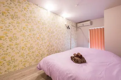 a teddy bear laying on a bed in a bedroom at AZEGAMI 2F in Tokyo