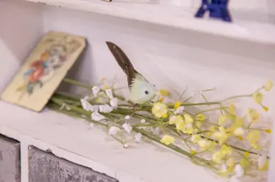 a bird is sitting on a shelf with flowers at AZEGAMI 2F in Tokyo