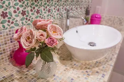 a vase with pink roses in it next to a sink at AZEGAMI 2F in Tokyo