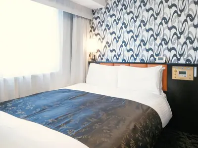 a bedroom with a bed with a blue and white wallpaper at APA Hotel Nihombashi Bakuroyokoyama Ekimae in Tokyo