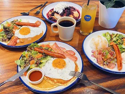 a wooden table with plates of breakfast foods and drinks at APA Hotel Nihombashi Bakuroyokoyama Ekimae in Tokyo