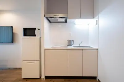 a small kitchen with a refrigerator and a microwave at Eisei Stay in Tokyo