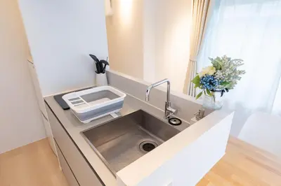a kitchen sink in a counter with a vase of flowers at Feel Asakusa Stay in Tokyo