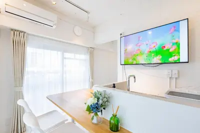 a living room with a table and a tv on the wall at Feel Asakusa Stay in Tokyo