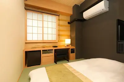 a bedroom with a desk and a bed and a window at Hotel Matsunoi in Tokyo