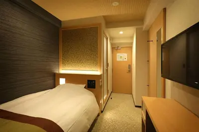 a hotel room with a bed and a flat screen tv at Hotel Matsunoi in Tokyo