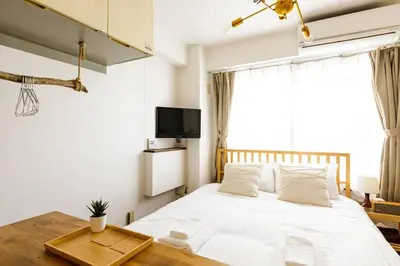 a bedroom with a white bed with a table and a tv at Maison d'Orme 503 in Tokyo