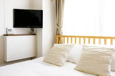 a bed with white pillows and a flat screen tv at Maison d'Orme 503 in Tokyo