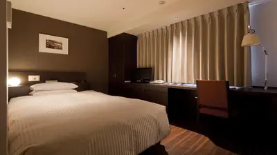 a bedroom with a bed and a desk and a window at Hotel Grand Hill Ichigaya in Tokyo