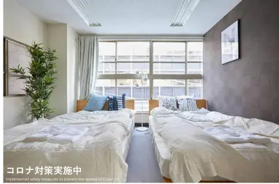 a room with two beds and a large window at TORA HOTEL Tokyo-Taito \u5bc5\u30db\u30c6\u30eb\u53f0\u6771B in Tokyo