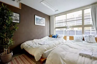 two beds in a room with a large window at TORA HOTEL Tokyo-Taito \u5bc5\u30db\u30c6\u30eb\u53f0\u6771B in Tokyo