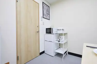 a small room with a door and a microwave at TORA HOTEL Tokyo-Taito \u5bc5\u30db\u30c6\u30eb\u53f0\u6771B in Tokyo