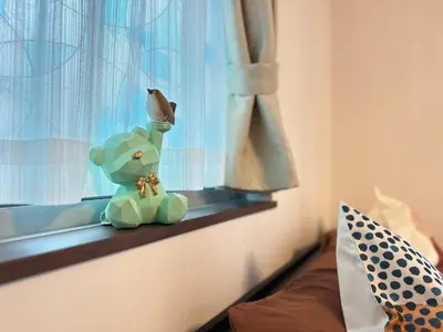 a small green teddy bear sitting on a window sill at nestay house tokyo shinjuku in Tokyo