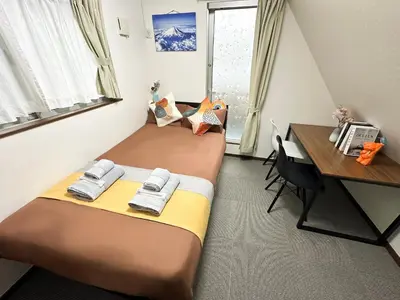 two beds in a small room with a desk and a desk at nestay house tokyo shinjuku in Tokyo