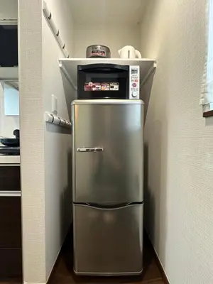 a small kitchen with a stainless steel refrigerator at nestay house tokyo shinjuku in Tokyo
