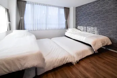 two beds in a bedroom with a brick wall at HOTEL LITTLE BIRD OKU-ASAKUSA / Vacation STAY 79448 in Tokyo