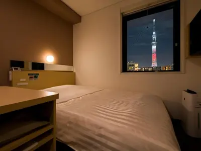 a bedroom with a bed and a window with a tower at Super Hotel Tokyo Kinshicho Ekimae / Vacation STAY 79355 in Tokyo