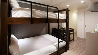 a bedroom with two bunk beds with white sheets at Minn Kamata in Tokyo