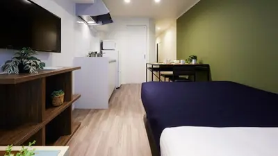 a bedroom with a bed and a kitchen with a desk at Minn Kamata in Tokyo