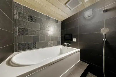 a white bath tub in a bathroom with black tiles at Hotel Lotus Koiwa (Adult Only) in Tokyo