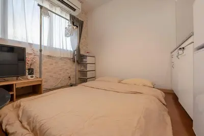 a bedroom with a bed and a tv and a window at Asakusa Panda Hostel in Tokyo