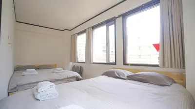 two beds in a room with two windows at TOKYO ICHIBAN ASAKUSA in Tokyo