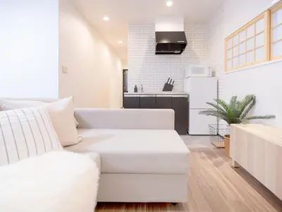 a living room with a white couch and a kitchen at Tsubame Hotel Asakusabashi 3 minutes walk from Asakusabashi Station Near Asakusa, Akihabara, and Ueno Cooking utensils and kitchen washing machine available Direct access to Haneda and Narita airports in Tokyo
