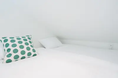 a white bed with a polka dot pillow on it at Miyako Shinjuku Hotel \u90fd-\u65b0\u5bbf- in Tokyo