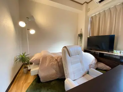 a bedroom with a bed and a chair and a television at Yoyogi Apartment 2-401 by Tranova in Tokyo