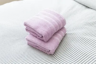 a pink towel sitting on top of a bed at Nakano Apartment hotel in Tokyo