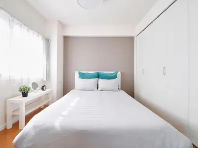 a white bedroom with a large bed and a window at Nakano Apartment hotel in Tokyo
